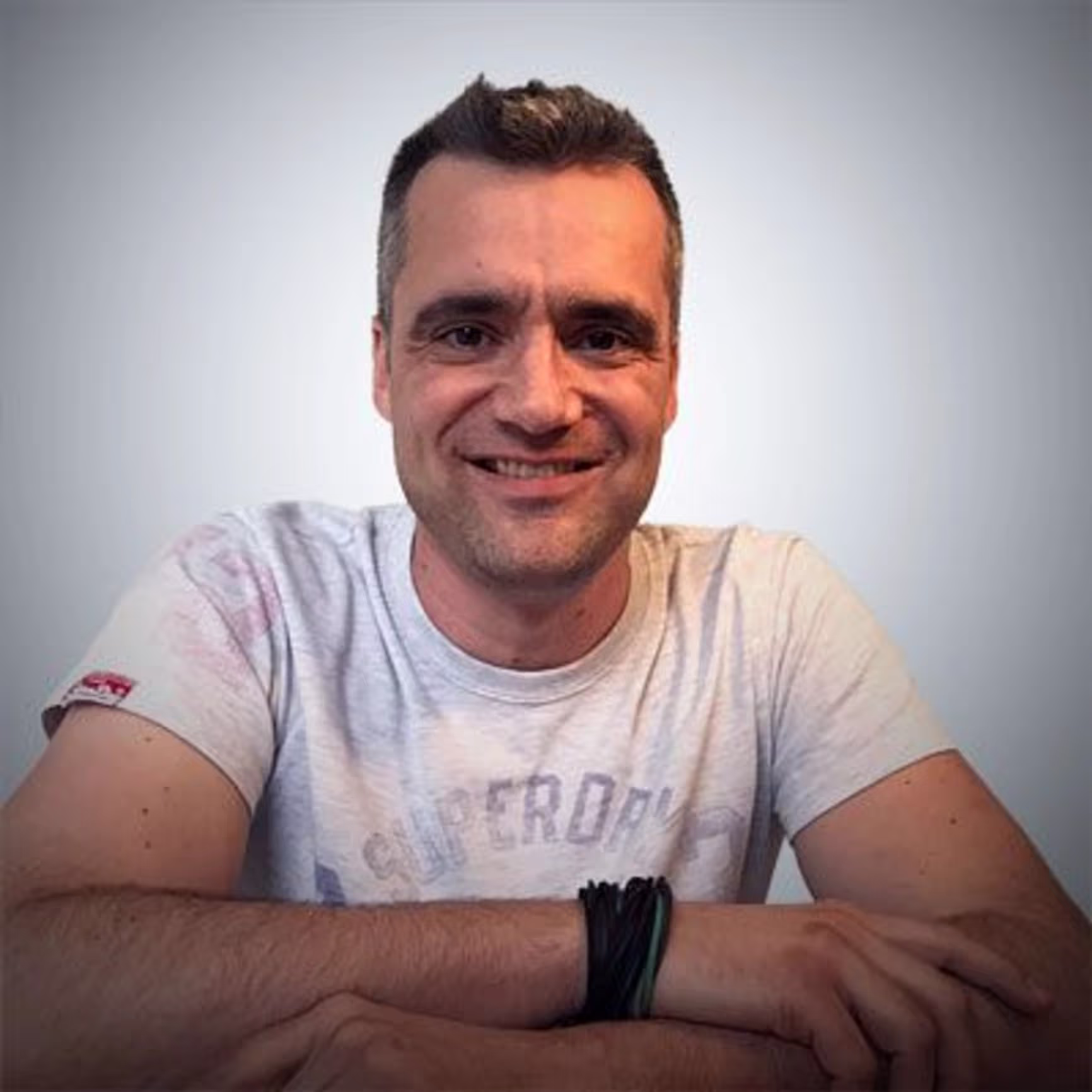 Foto eines Mannes mit weißem T-Shirt, der in die Kamera lächelt